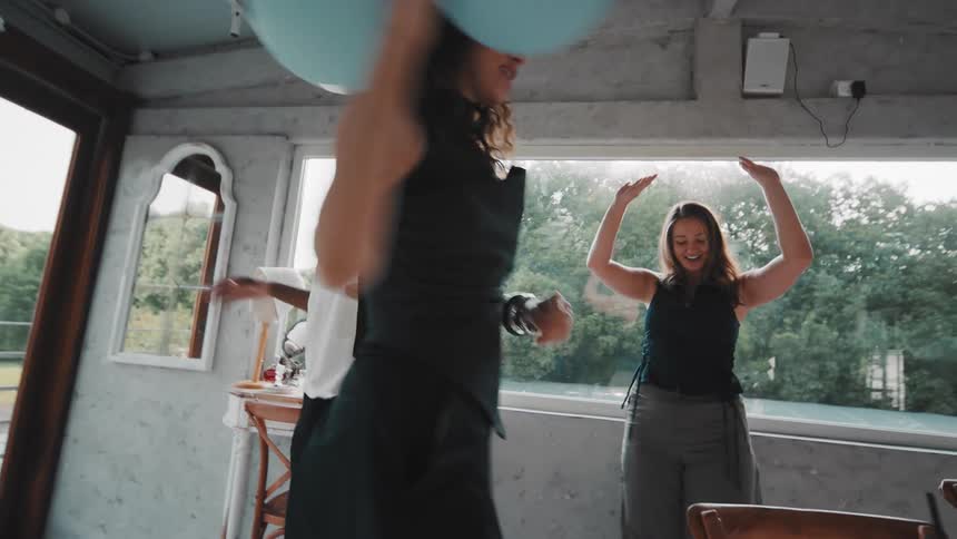 An energetic group of diverse friends have fun dancing together in slow motion at an indoor celebration