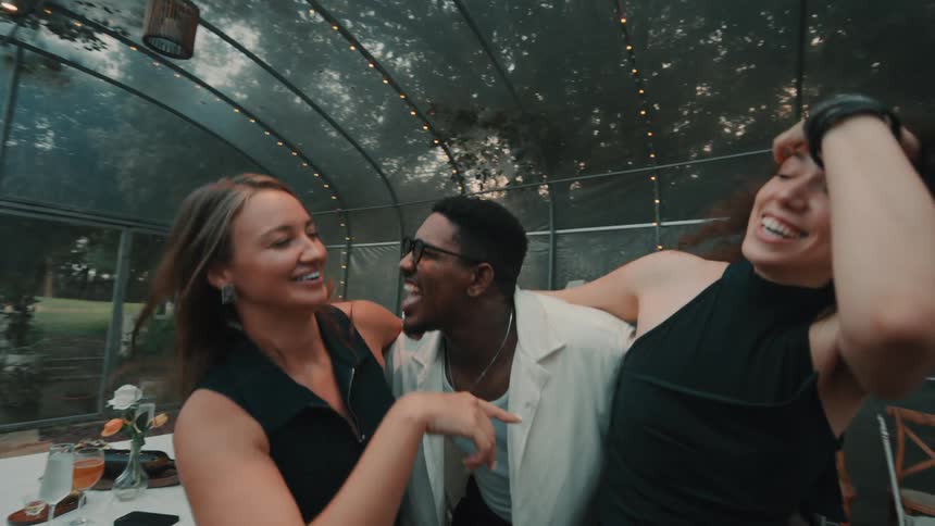 A group of diverse and joyful friends dance, laugh, and have fun together in slow motion at an outdoor party
