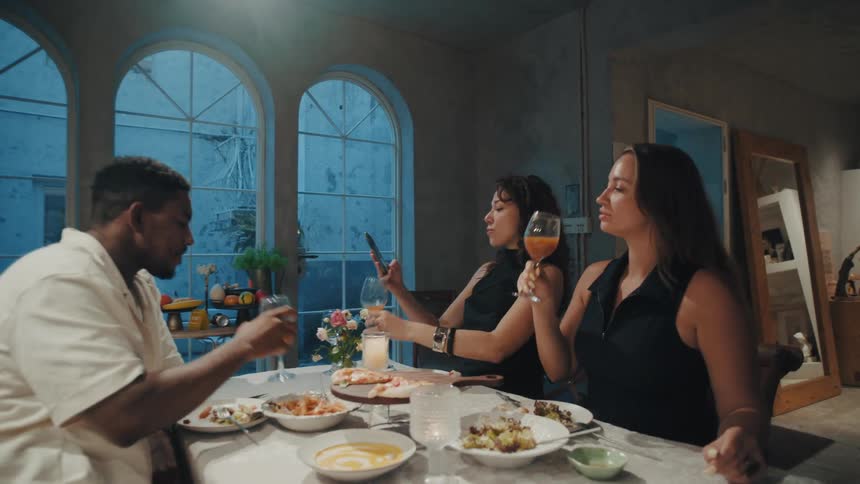 Happy multiethnic friends enjoy a festive dinner, toasting with drinks and taking a selfie to capture the moment