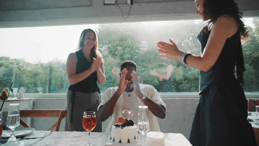 In slow motion, friends surprise a young man with a birthday cake, and he reacts with pure joy and excitement