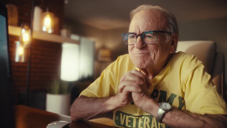 A senior veteran laughs with joy during a video call at his desk, then smiles thoughtfully in his home office