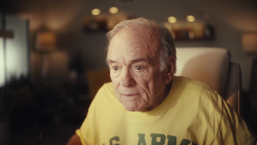 An elderly US Army veteran gets angry and yells at his computer screen in a dimly lit living room