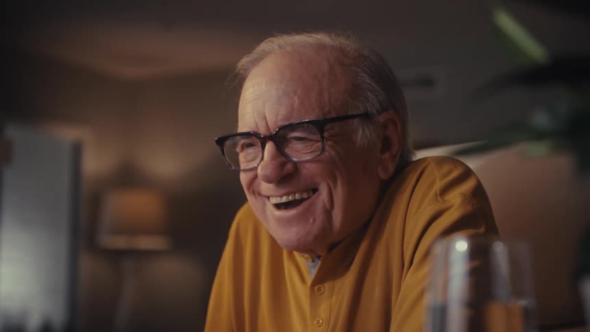 Close-up slow-motion shot of a delighted elderly man in glasses, laughing and celebrating with joy