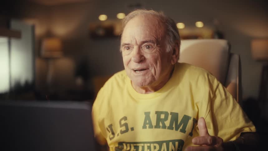 A U.S. Army veteran's face goes from extreme shock to pure joy and laughter as he watches something on his computer at home