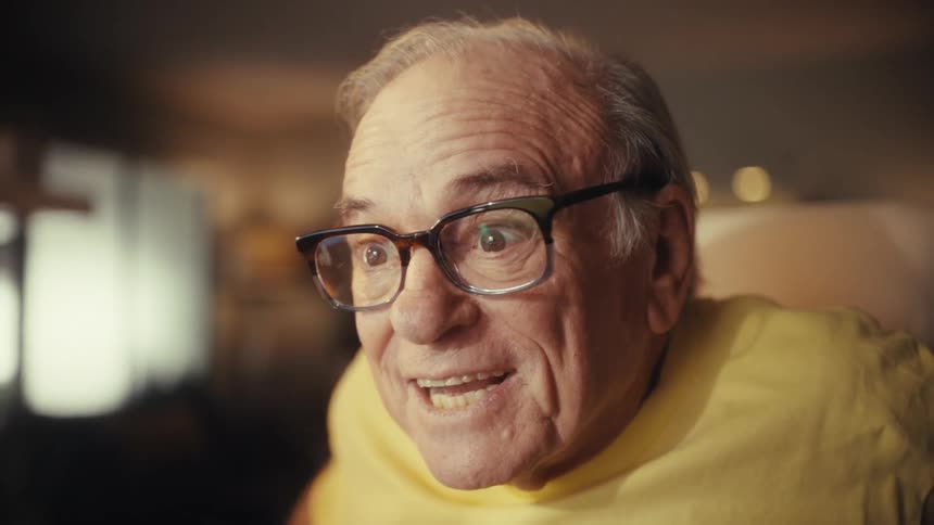 An elderly US Army veteran gets incredibly excited and takes off his glasses in disbelief while looking at his computer