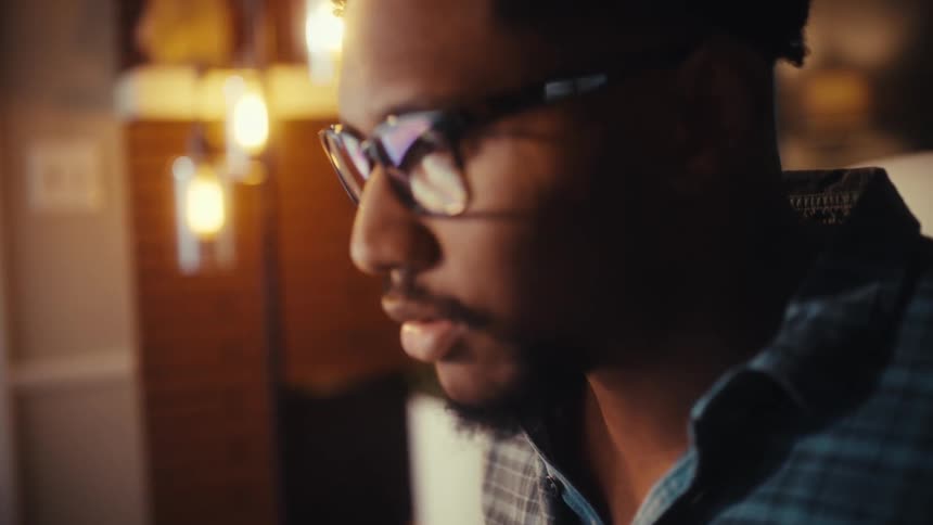 A close-up shot pans from a man's hands typing on a keyboard up to his focused face as he works on the computer