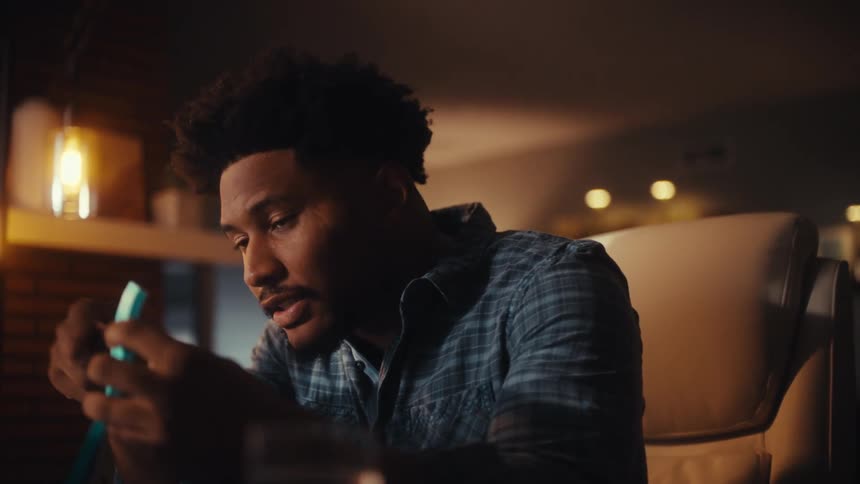 An African American entrepreneur passionately pitches his ideas from a notebook during a late-night video conference in his home office