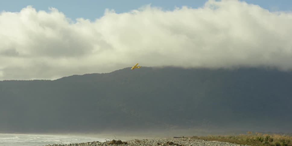 A yellow plane glides by the clouds