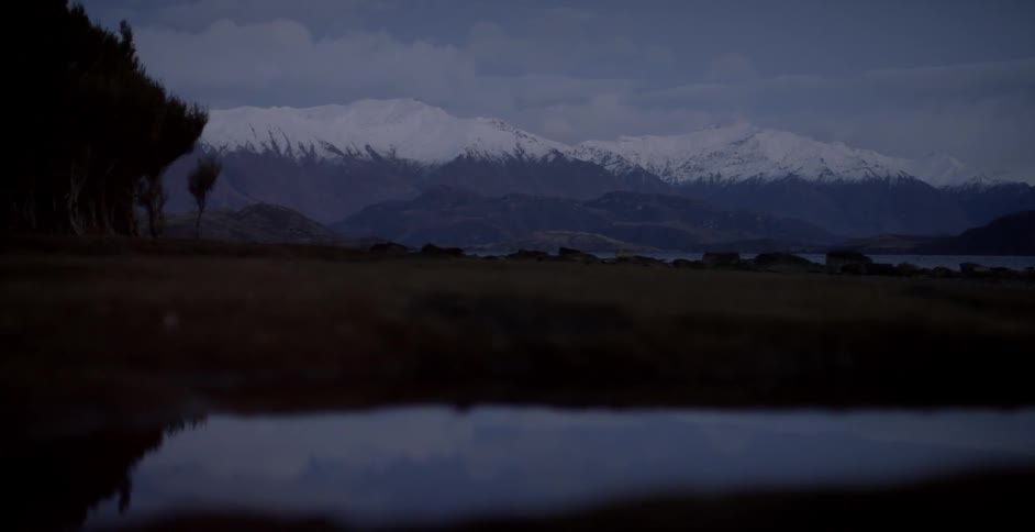 Snow capped mountains stand in the distance at dusk