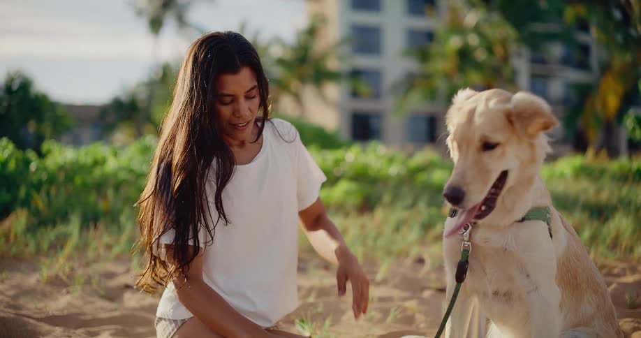 A young woman enjoys a quiet moment with her adorable golden retriever on a sunny beach in slow motion
