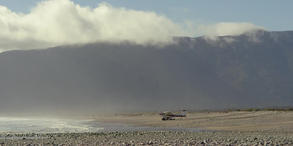 The beach is foggy with water crashing against the sand