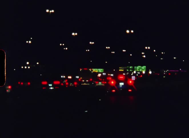 Vintage 8mm film captures an out-of-focus view of heavy traffic on a busy highway at night