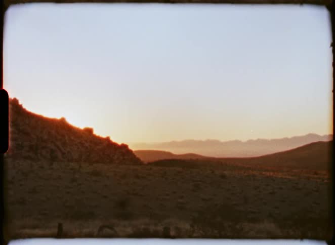 Vintage Super 8 film captures a serene sunrise over a beautiful desert mountain landscape