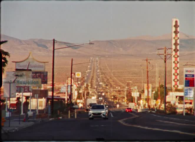 A vintage-style shot of traffic on the long, straight desert highway in Baker, California, at golden hour