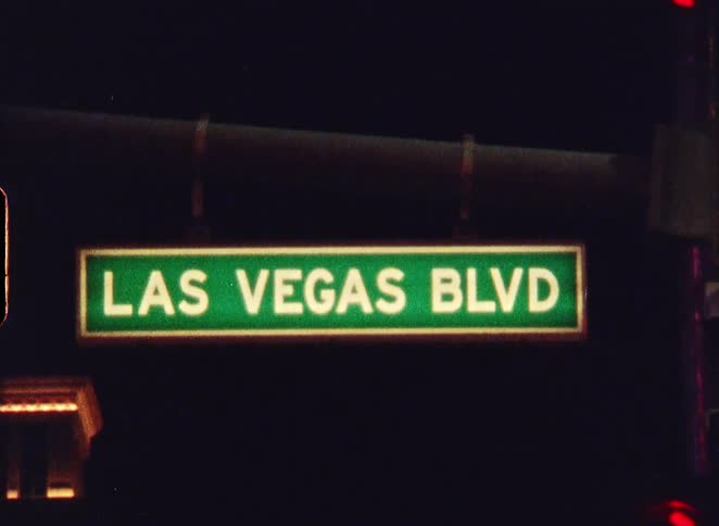 A grainy, vintage close-up shot of the illuminated 'Las Vegas Blvd' street sign at night
