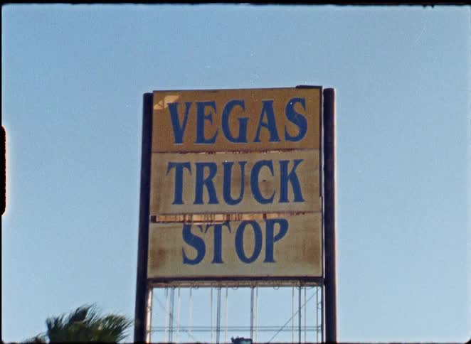 A vintage-style shot of a weathered 'Vegas Truck Stop' sign against a clear blue sky
