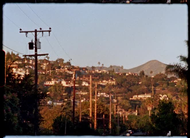 A vintage, static shot of a quiet hillside neighborhood bathed in the warm glow of the golden hour