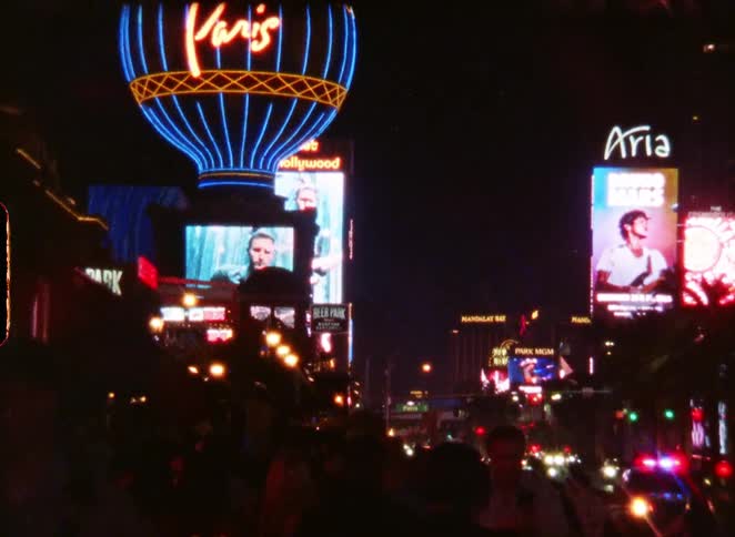 A vintage film captures the vibrant and busy Las Vegas strip at night, featuring the iconic Paris and Aria hotel neon signs