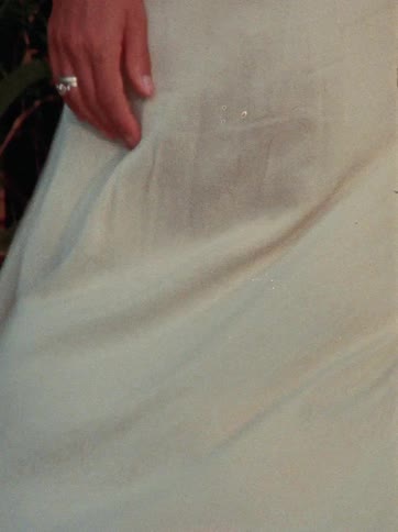 A close up slow motion shot of a woman's white dress swaying in the breeze against a background of reeds