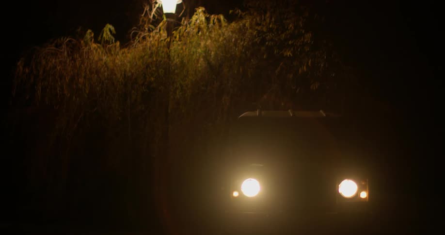 A car in the dark starts turning it's light on