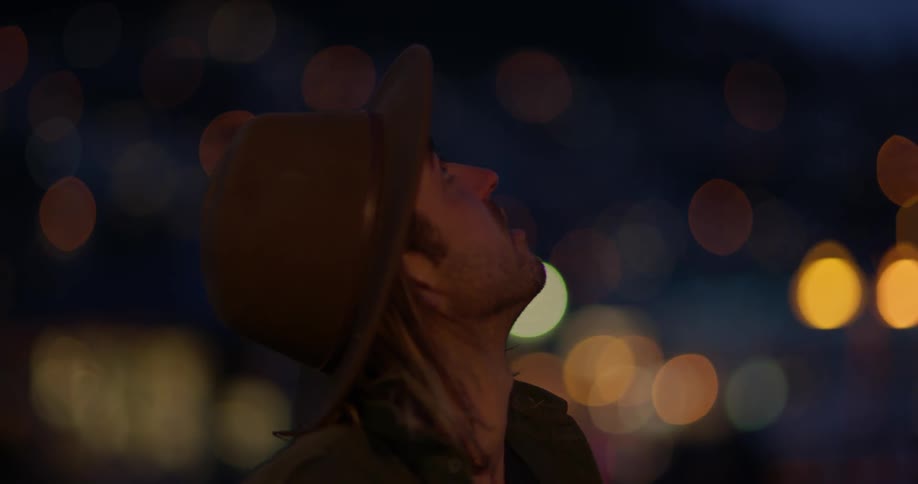 A man in a hat looks up at the sky