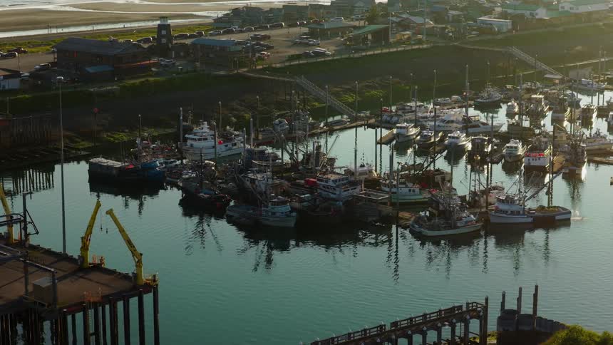 A tranquil fishing boat harbor is illuminated by the warm, golden light of sunset