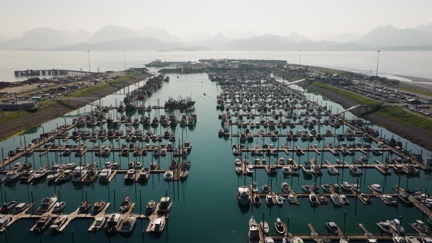 An epic aerial view reveals a vast harbor filled with hundreds of docked fishing boats and yachts, set against a backdrop of hazy mountains