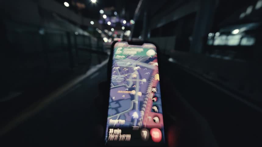 POV of a person walking through a city underpass at night while following a GPS navigation map on their smartphone