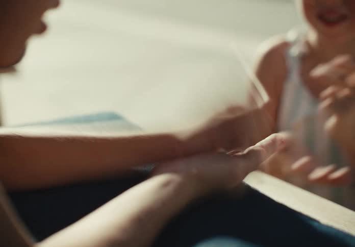 A close-up slow-motion shot of two people playing a game of rock, paper, scissors in the bright sunlight
