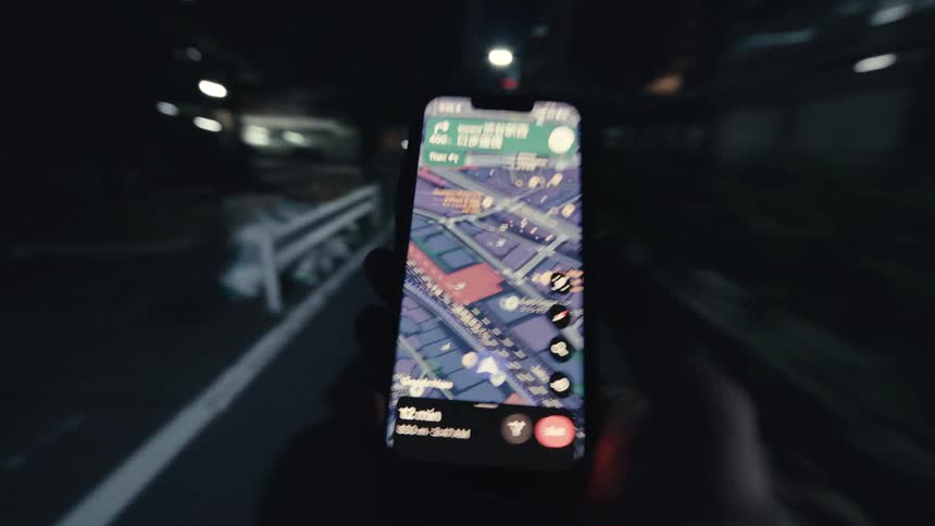 A disorienting point-of-view shot of a person walking through a city at night while following GPS navigation on their smartphone