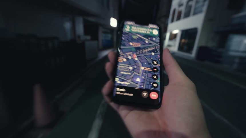 A first-person view of navigating through a dark urban alley at night, guided by a glowing map on a smartphone