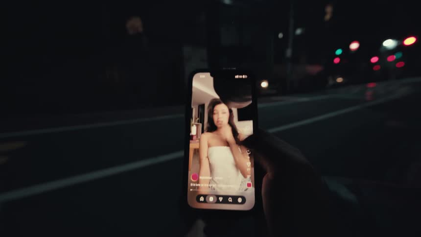 A first-person view of a hand quickly scrolling through a social media feed on a smartphone at night