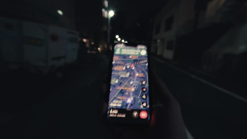 First-person view of someone navigating a dark city street at night with a map on their smartphone