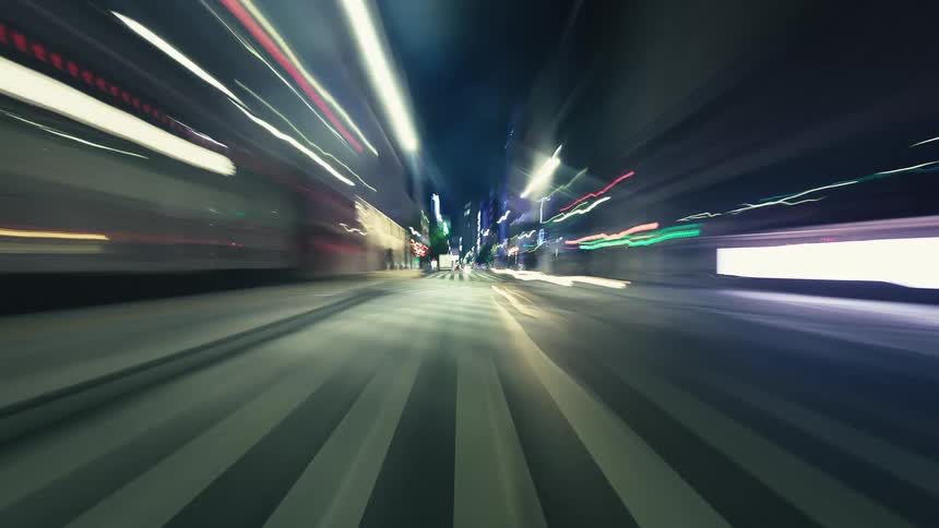A thrilling POV hyperlapse captures a high-speed drive through a vibrant city at night, with colorful light trails creating a futuristic feel