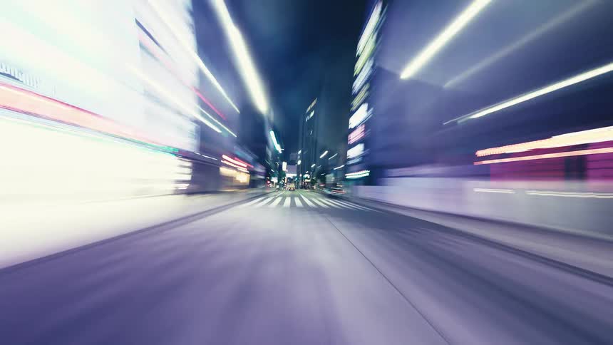A fast-paced, motion-blurred POV hyperlapse of driving through a city at night, with light trails streaking past