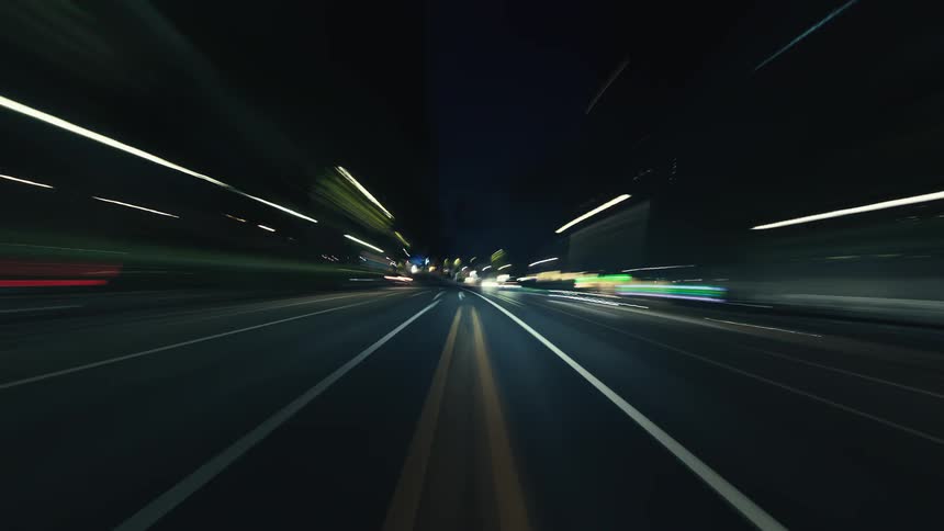 A fast-paced hyper-lapse captures the surreal beauty of a night drive through city streets, with colorful lights streaking across the screen
