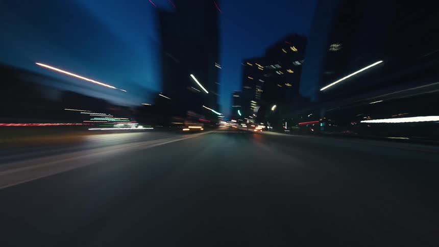High-speed POV hyperlapse drive through a modern city at night with blurred light trails