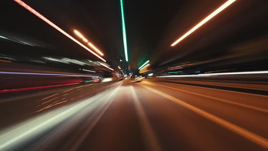 A mesmerizing time-lapse drive through a futuristic city at night, with light trails creating a sense of warp speed