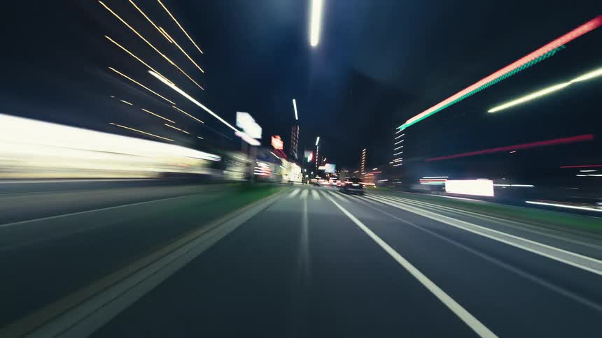 A dizzying first-person hyperlapse captures the high-speed journey through a modern city at night, with vibrant light trails streaking past