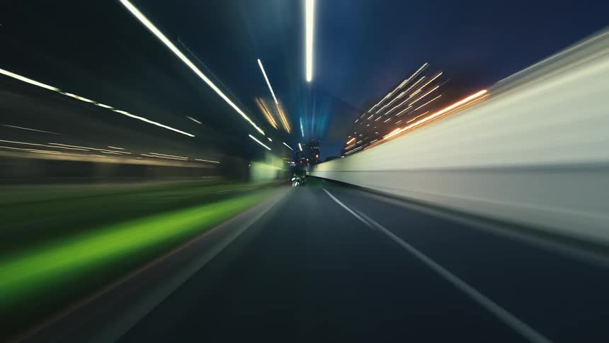 A dynamic POV hyperlapse captures the energetic light trails of a fast night drive through the city