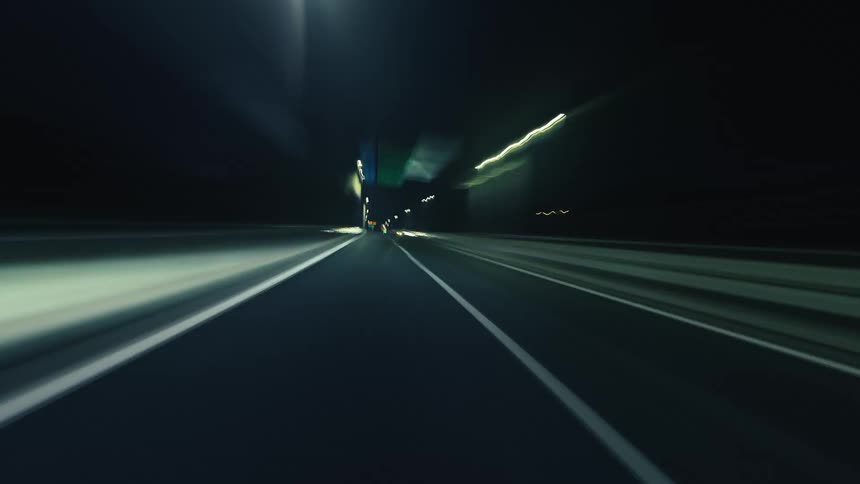 A fast-paced point-of-view hyper-lapse speeds through a dark city and illuminated tunnels, creating abstract light trails