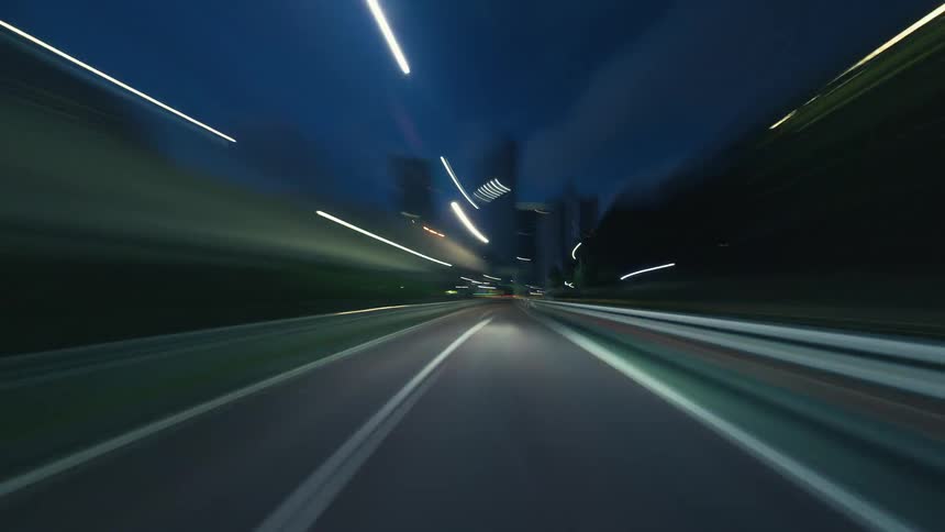 An exhilarating point-of-view hyper-lapse drive through a modern city at night, with streetlights blurring into vibrant streaks of light
