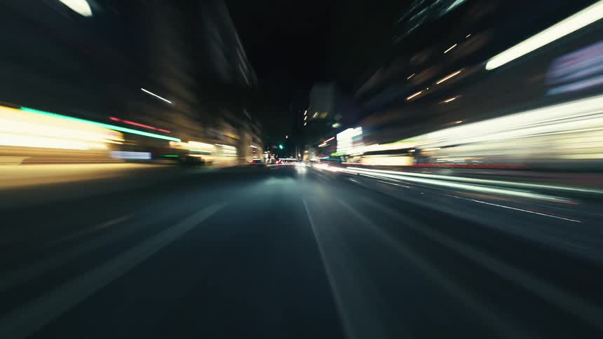 High-speed POV hyperlapse driving through city streets at night, creating mesmerizing light streaks