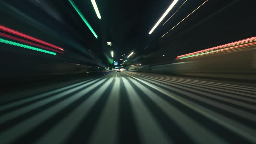 A vibrant point-of-view timelapse shows driving through a city street at night with streaks of light