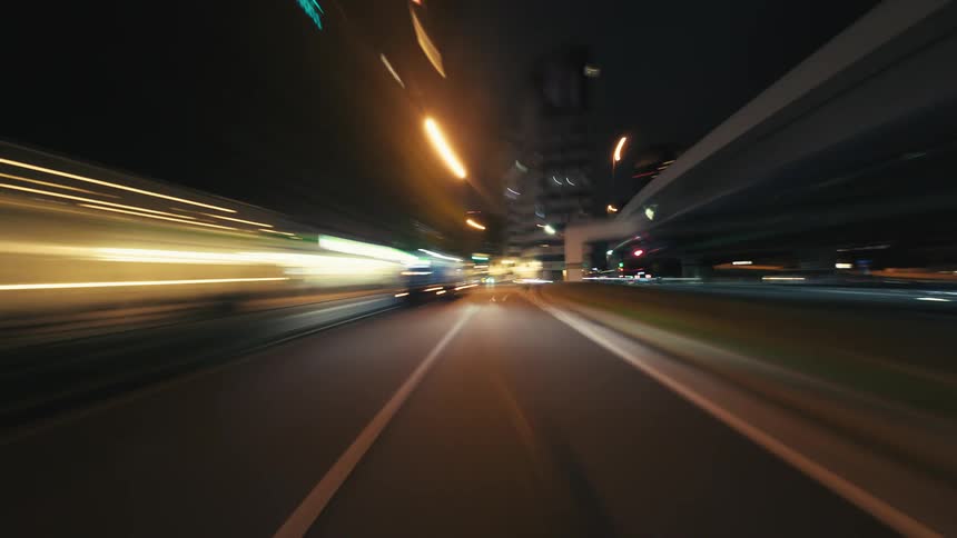 A dynamic hyperlapse from a driver's point of view captures the glowing light streaks of a bustling city at night