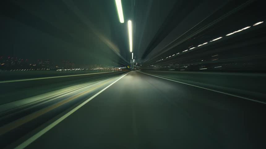 A futuristic POV timelapse of a car speeding through city highways and tunnels at night, creating mesmerizing light trails