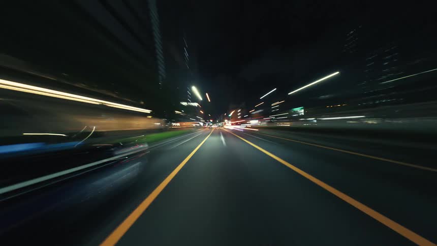 A high-speed point-of-view hyperlapse of driving through a bustling city at night with vibrant light trails