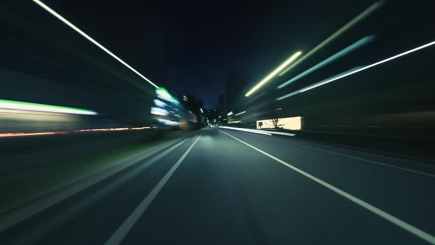 An immersive point-of-view hyperlapse captures the energetic blur of city lights while driving through urban streets at night