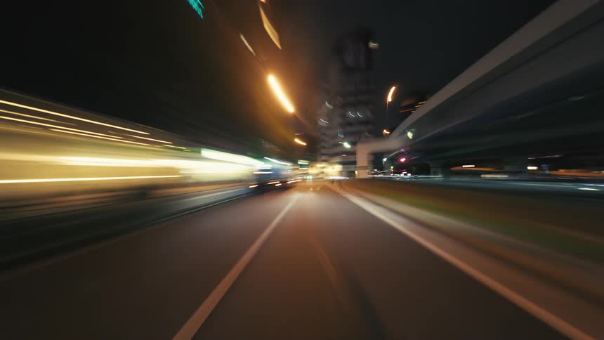 A dynamic POV hyperlapse of driving through a futuristic city at night, with vibrant light trails blurring past