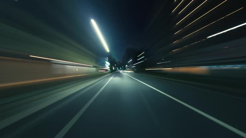 A dizzying hyperlapse from a car driving through city streets at night, creating vibrant streaks of light
